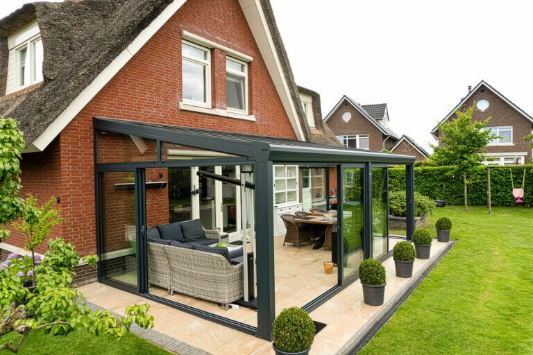 Anthrazit Terrassenüberdachung mit Glasschiebewänden Terrassenüberdachung Classic L in Anthrazit mit Glasschiebewänden an Backsteinhaus