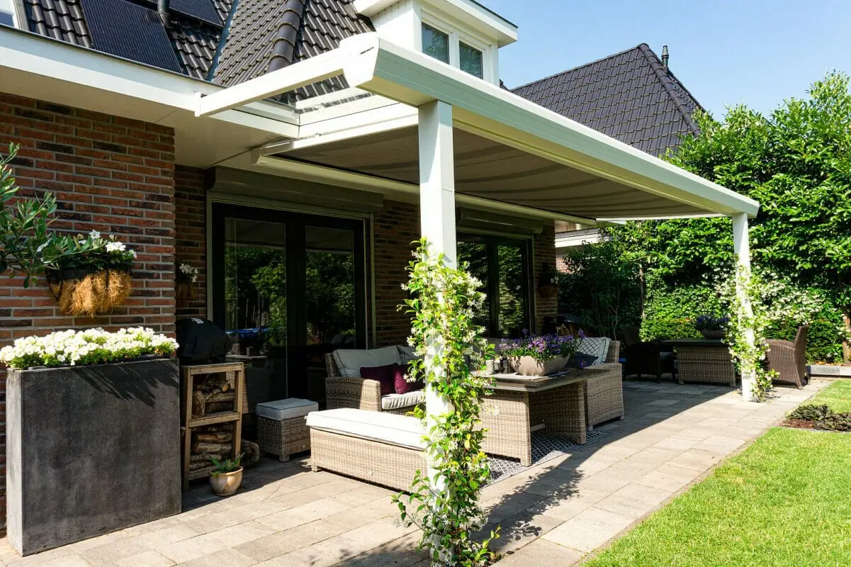 Weiße Alu-Terrassenüberdachung mit Lounge Weiße Alu-Terrassenüberdachung mit Lounge-Möbeln an Klinkerhaus