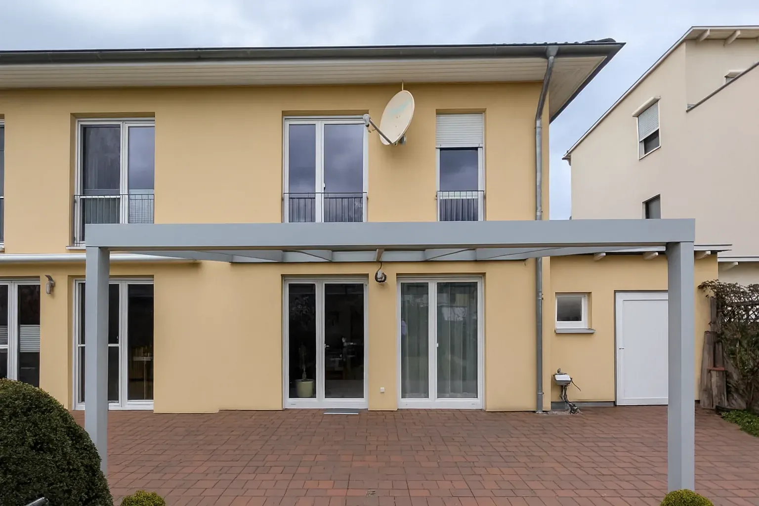 Classic L Plus mit hellen Aluminiumprofilen über einer Klinkerterrasse